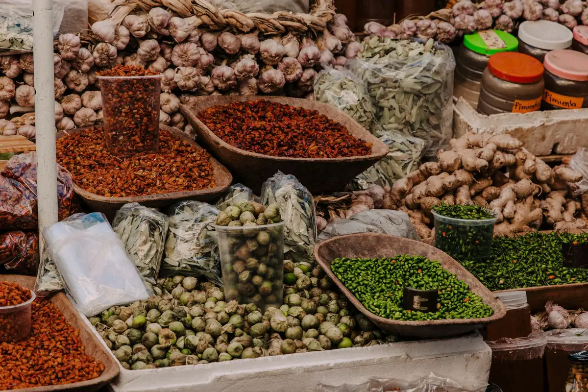 Marché local avec étals de légumes frais, herbes aromatiques et épices en vrac