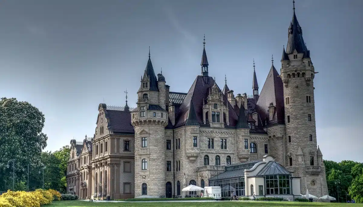 Façade ancienne en pierre blonde d'un château médiéval avec portes sculptées et volets patinés