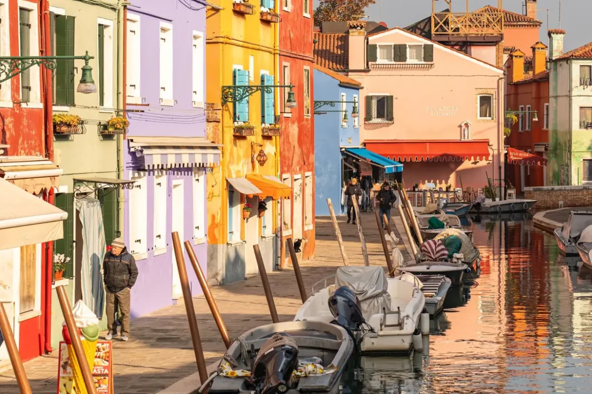 Ruelle étroite d'un village côtier méditerranéen avec façades colorées et volets en bois