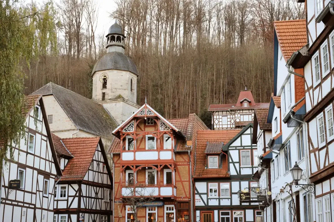 Rue pavée d'un village normand avec maisons à colombages et toitures en ardoise sous lumière douce.