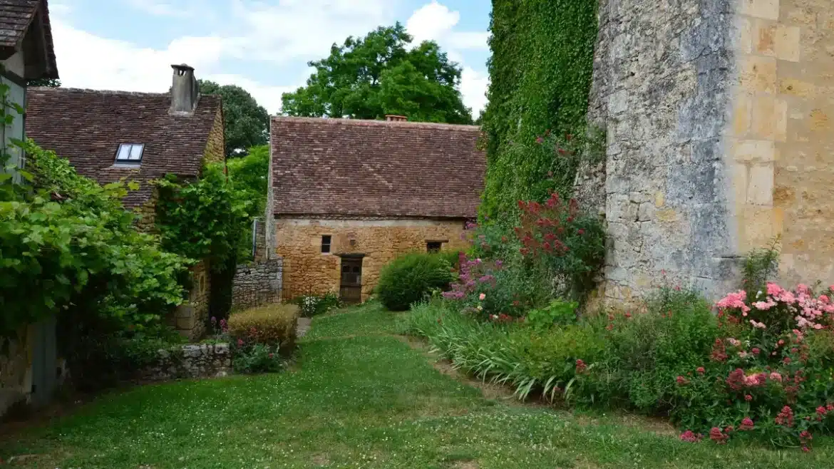 Ruelle pavée d'un village breton avec maisons à colombages décorées de fleurs colorées