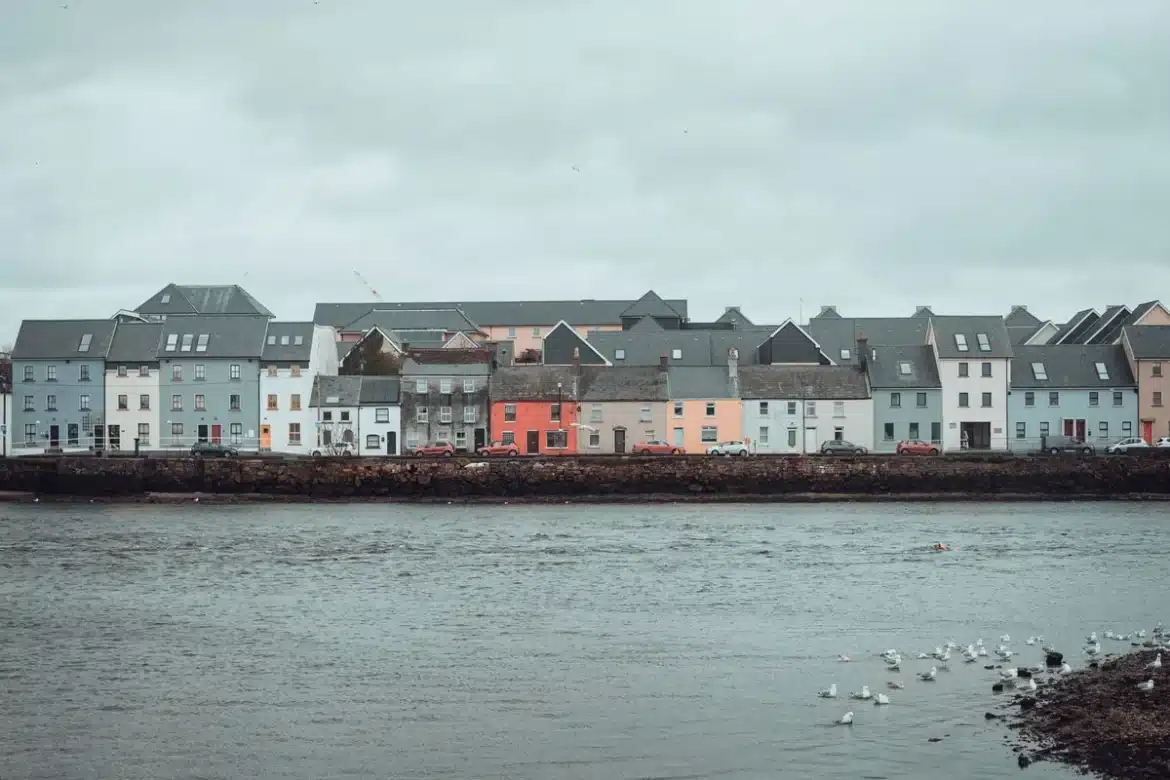 Baie côtière bretonne avec maisons colorées en gradins et bateaux de pêche ancrés