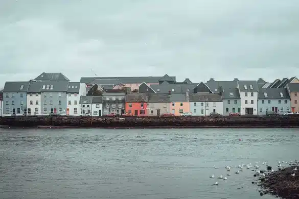 Baie côtière bretonne avec maisons colorées en gradins et bateaux de pêche ancrés