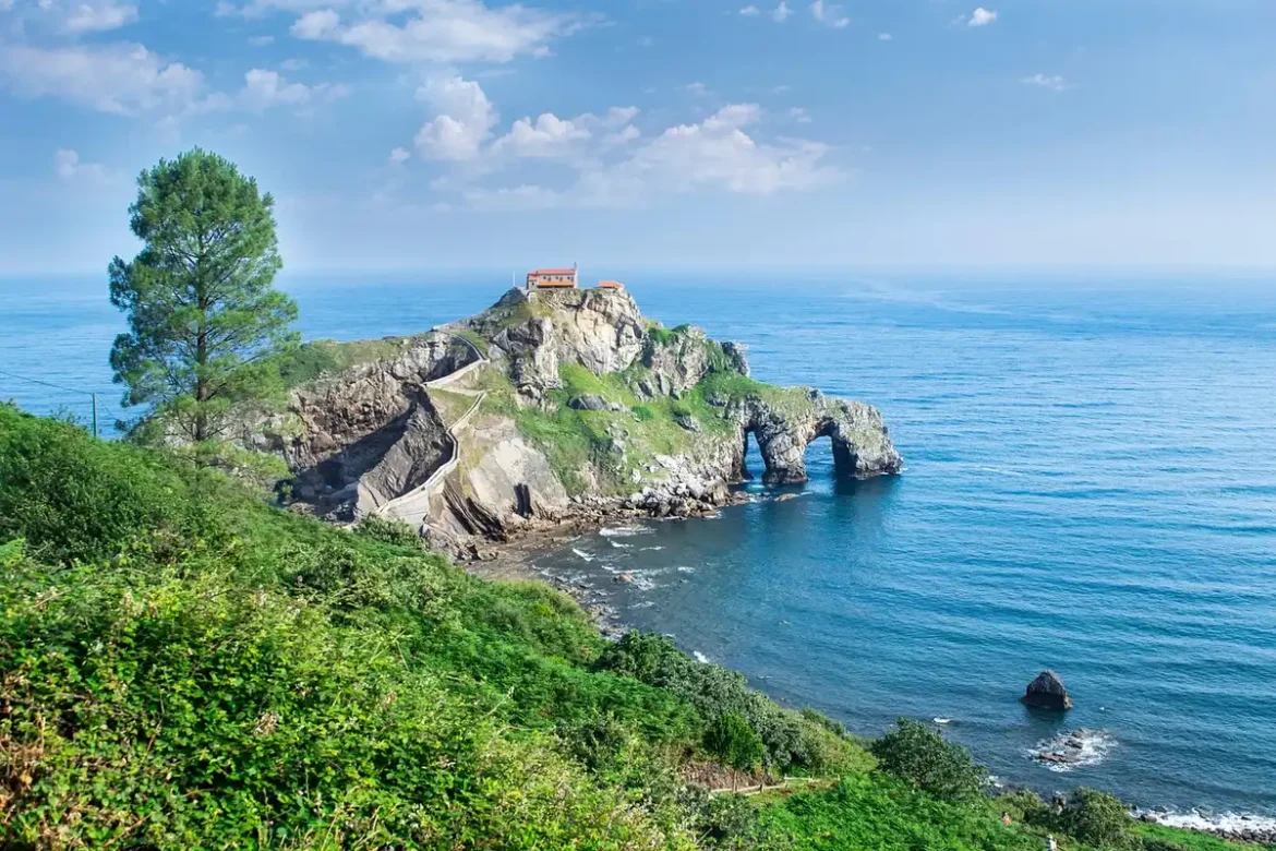 Vue diurne d'un village fortifié sur des falaises avec remparts et maisons colorées face à l'océan