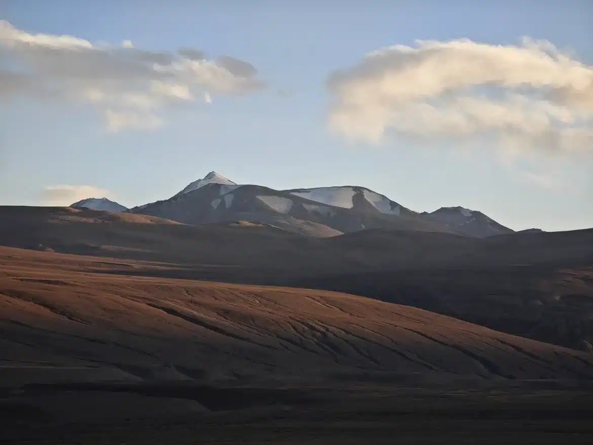 Groupe de randonneurs anonymes dans une forêt de montagne près d'un lodge et d'un volcan brumeux