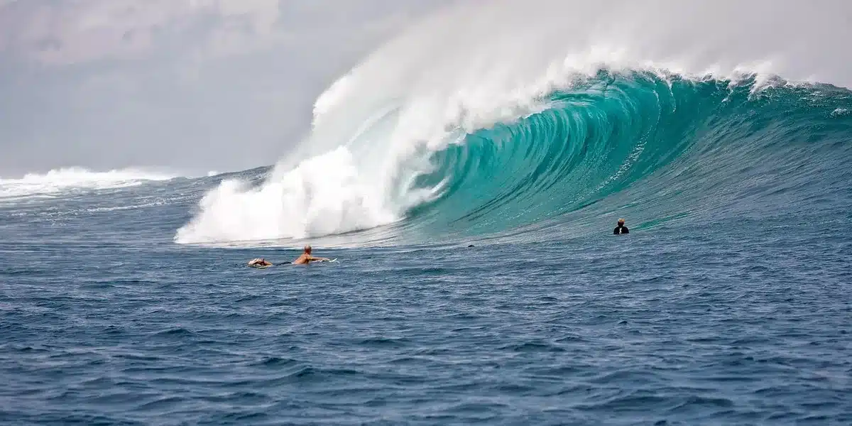 Surfeurs sur une plage de sable avec vagues régulières