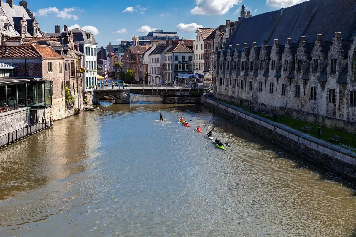 Canoé glissant sous un pont roman au-dessus d'une rivière tranquille bordée d'architecture médiévale