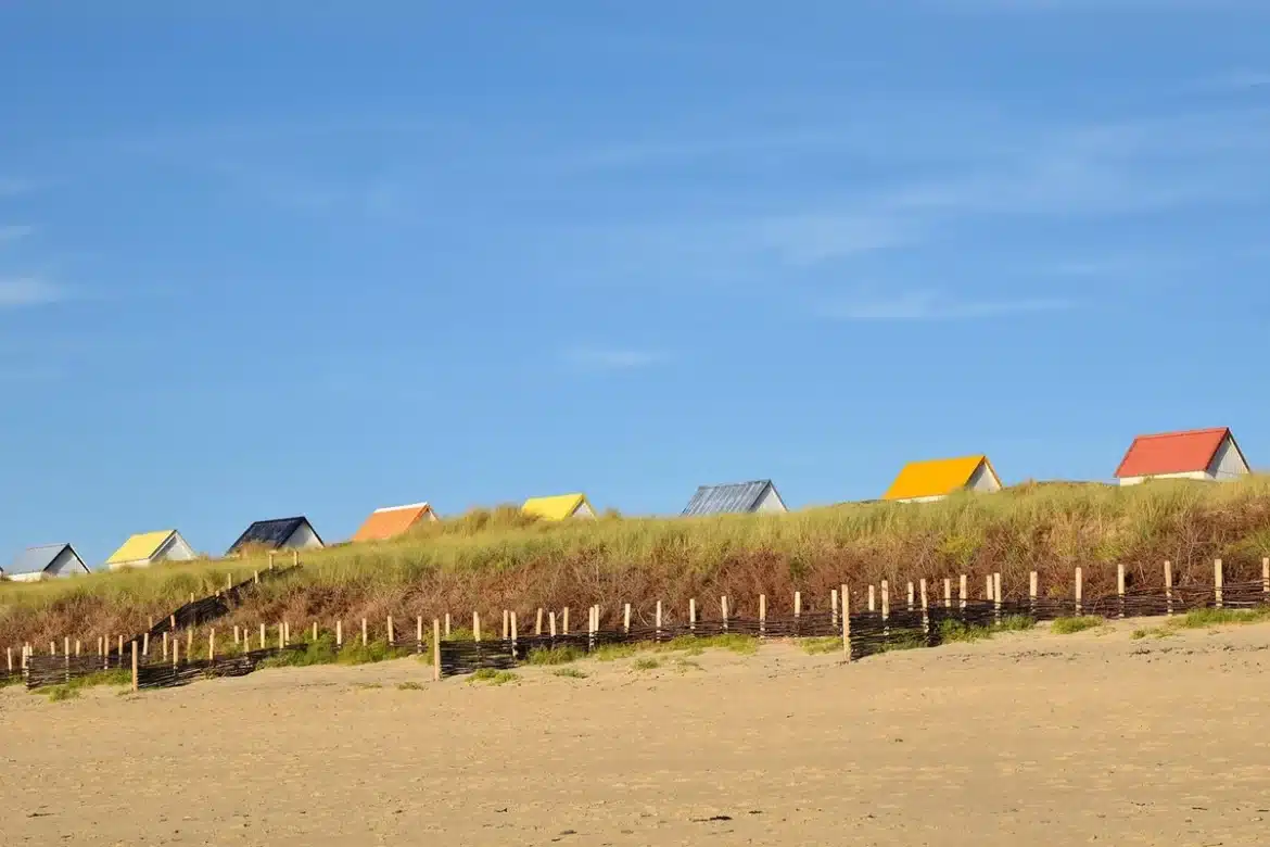 Promenade balnéaire avec cabines colorées et façades Belle Époque le long d'un port normand