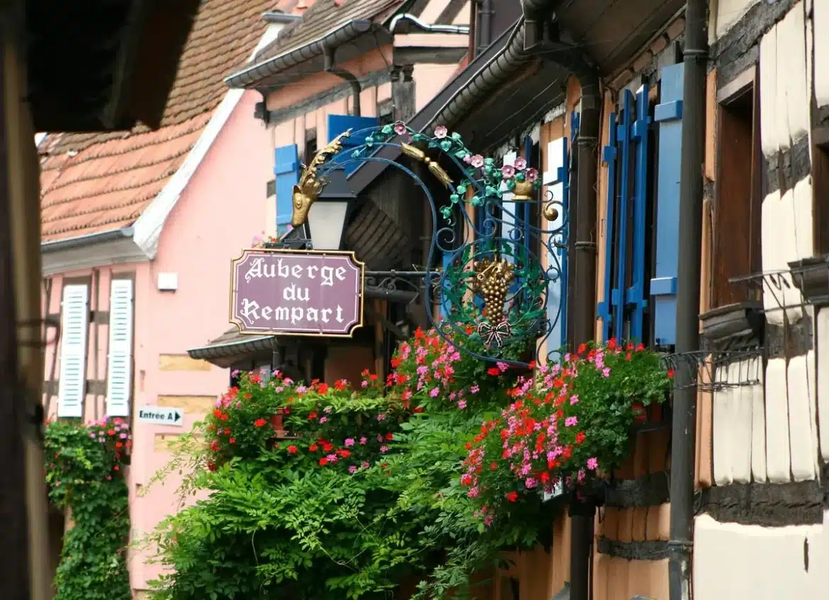 Rue pavée d’un village alsacien avec maisons à colombages et marché en journée