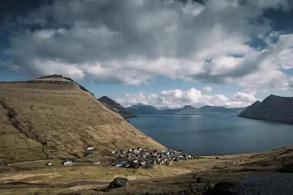 Berge de lac alpin en plein jour, sentier menant à des maisons de pierre et pâturages